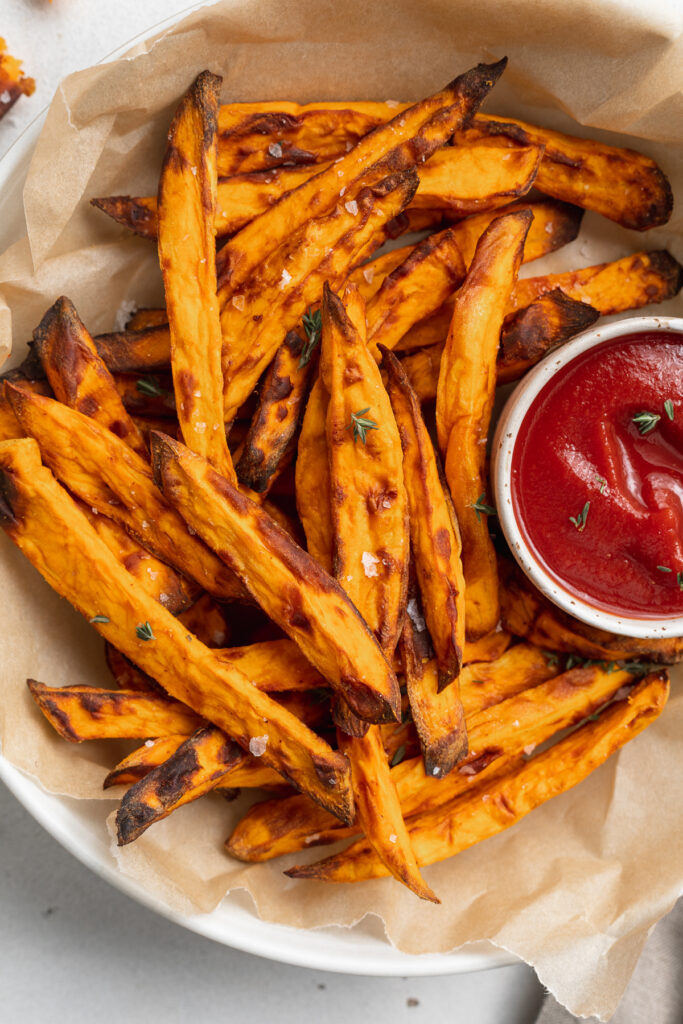 close-up overhead image of air fryer sweet potato fries on a plate with ketchup on the side