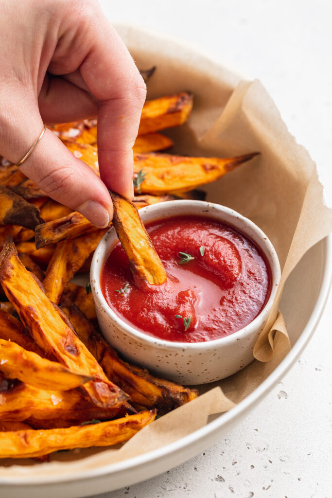 air fryer sweet potato fries being dipped into ketchup