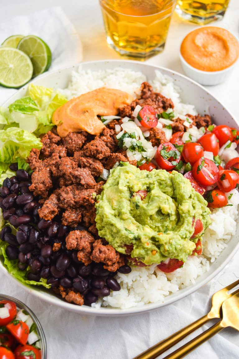 Loaded burrito bowls with a side of pico de gallo, fresh limes, and beer.