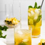 club soda being poured into a pineapple mojito