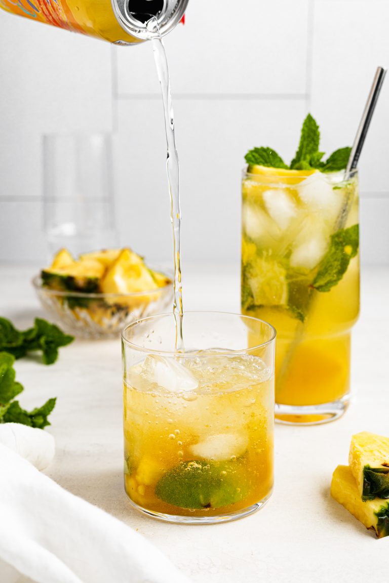 club soda being poured into a pineapple mojito