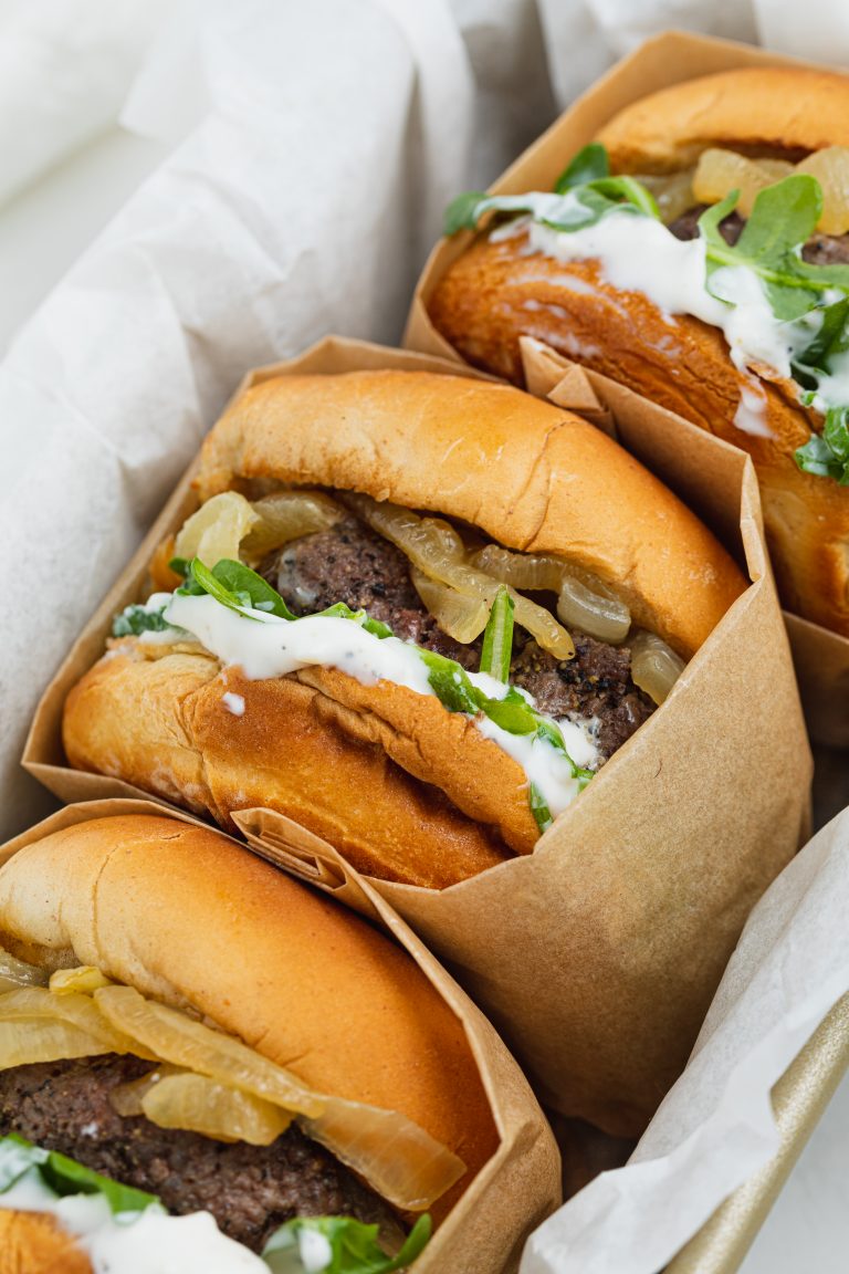 close up image of caramelized onion burgers in a baking pan