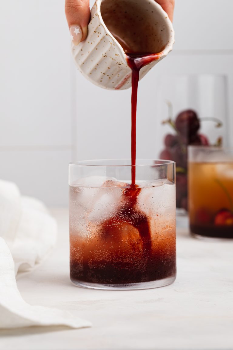 cherry cordial being poured into a glass of ice and sparkling water