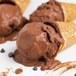 three cones of vegan chocolate ice cream lying on a table