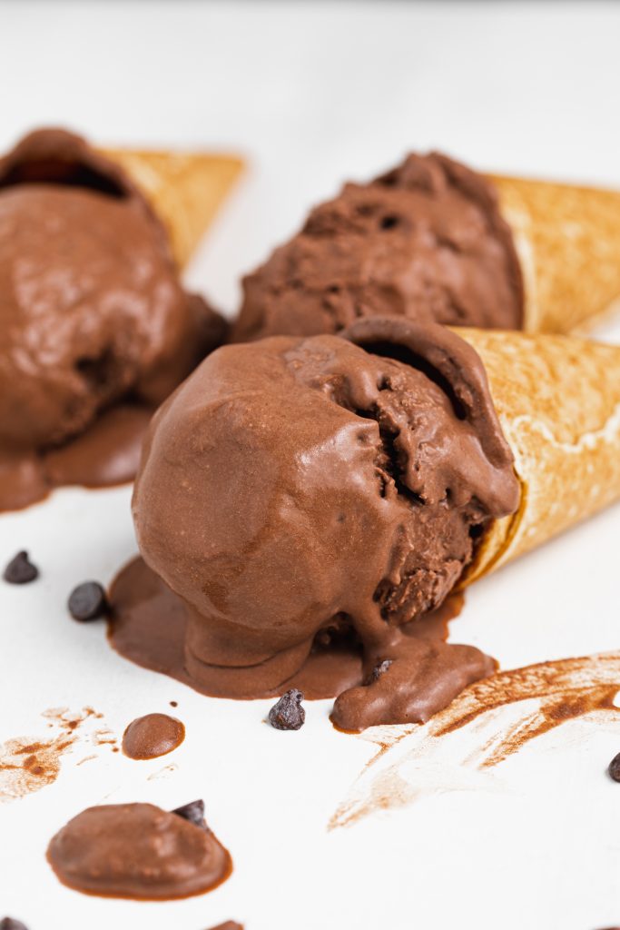 three cones of vegan chocolate ice cream lying on a table