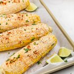 vegan elote on a baking sheet with fresh lime wedges