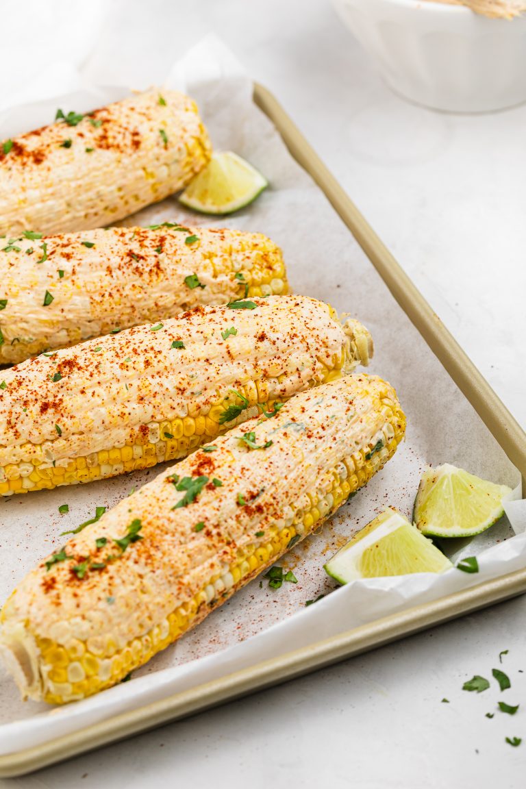 vegan elote on a baking sheet with fresh lime wedges