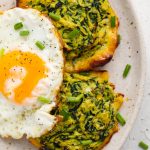 two zucchini hash browns on a plate with a fried egg on top