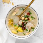 overhead image of a bowl of dairy-free clam chowder with gluten-free crackers on the side