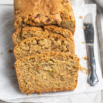 sliced gluten-free zucchini bread on a baking sheet with a knife.