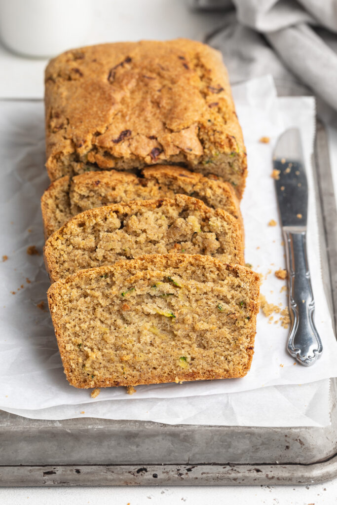 sliced gluten-free zucchini bread on a baking sheet with a knife.