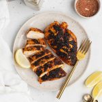 overhead image of blackened chicken on a plate with spices around the plate