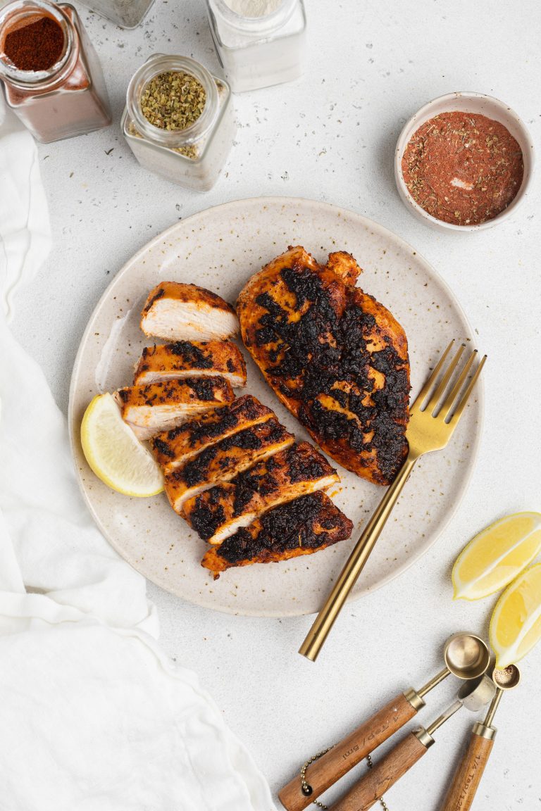overhead image of blackened chicken on a plate with spices around the plate