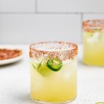 two spicy cucumber margaritas with spicy salt rim on the side