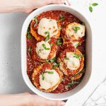 holding a baking dish with vegan eggplant parmesan inside