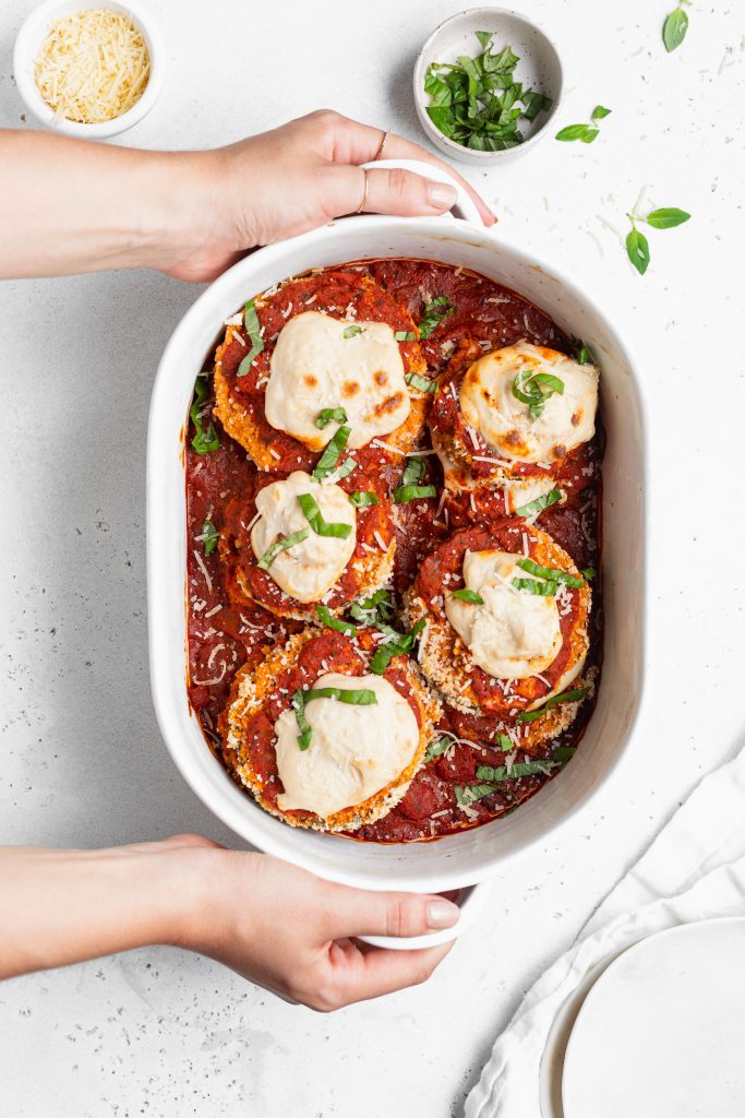holding a baking dish with vegan eggplant parmesan inside