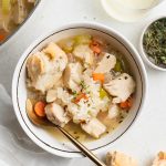overhead image of leftover turkey and rice soup with bread, wine, and fresh thyme on the side
