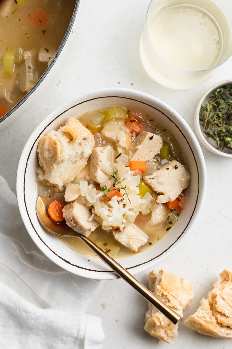 overhead image of leftover turkey and rice soup with bread, wine, and fresh thyme on the side