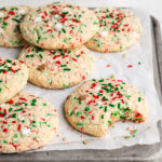 gluten-free christmas cookies on a baking sheet, one with a bite taken out.