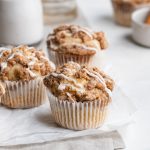 gluten-free coffee cake muffins on parchment paper with milk on the side