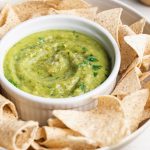 close-up image of guacamole salsa with chips on the side
