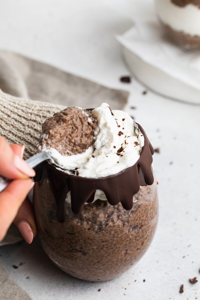 spoon scooping chocolate chia pudding out of a cup
