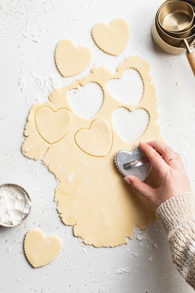 cutting out gluten-free sugar cookie dough into heart shapes