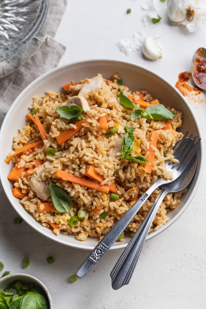 Thai fried rice in a serving bowl with a fork and a spoon