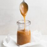 3 ingredient vegan caramel sauce in a small jar with a spoon