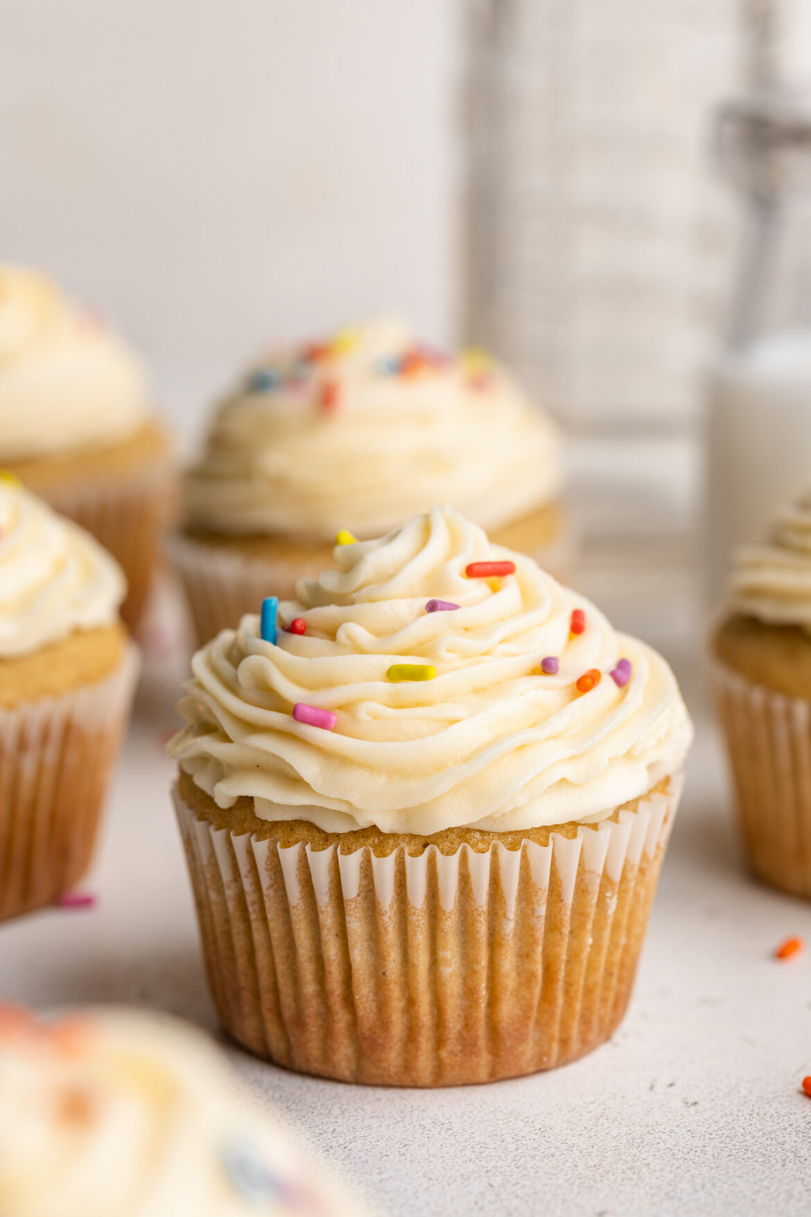 Best Ever Gluten-Free Vanilla Cupcakes close up image of a gluten-free vanilla cupcake with vanilla frosting and rainbow sprinkles.