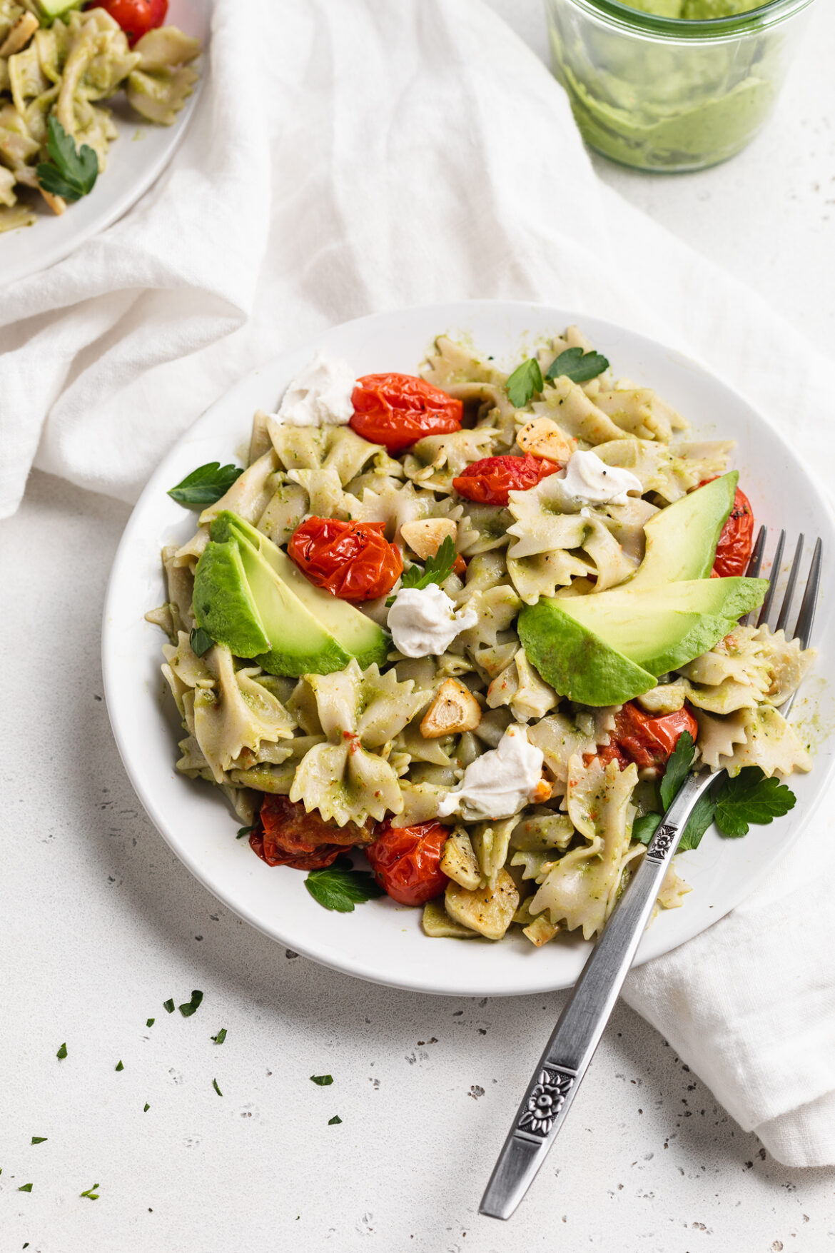 Avocado Pasta with Roasted Garlic and Tomatoes avocado pasta on a plate with a fork