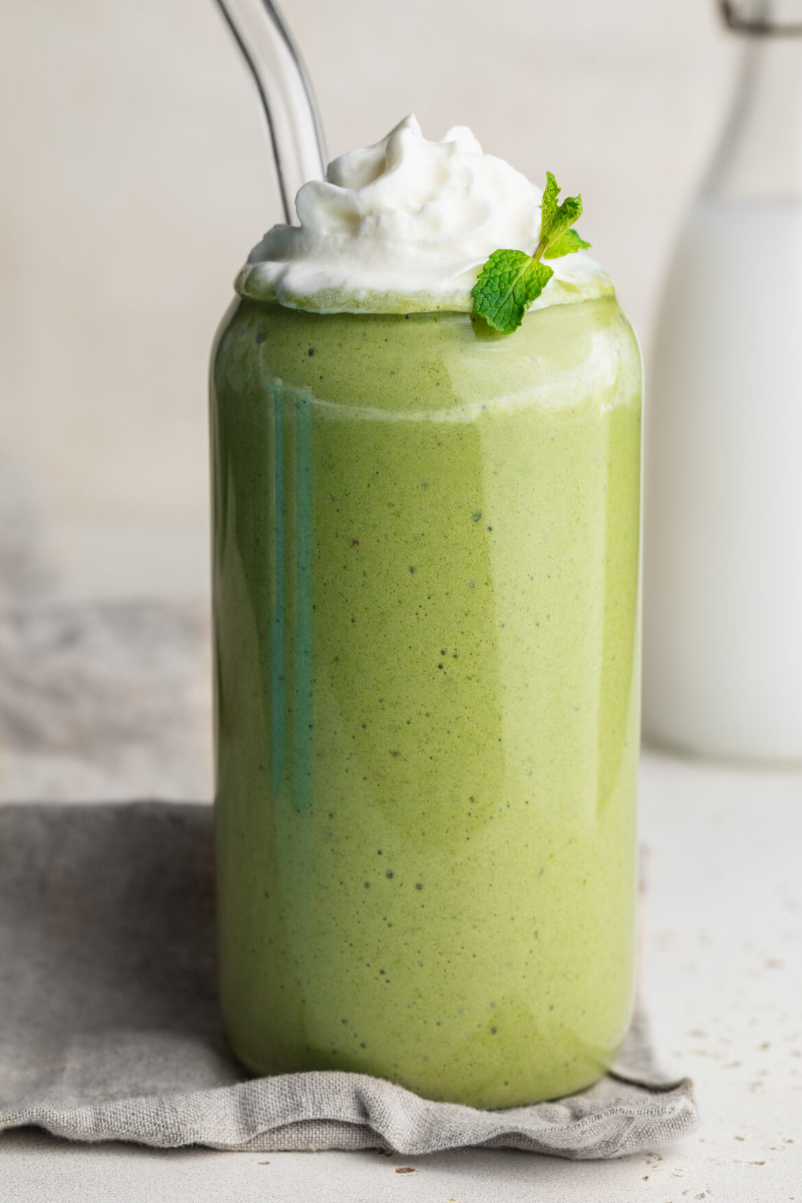 healthy shamrock shake in a glass with whipped cream and fresh mint on top.