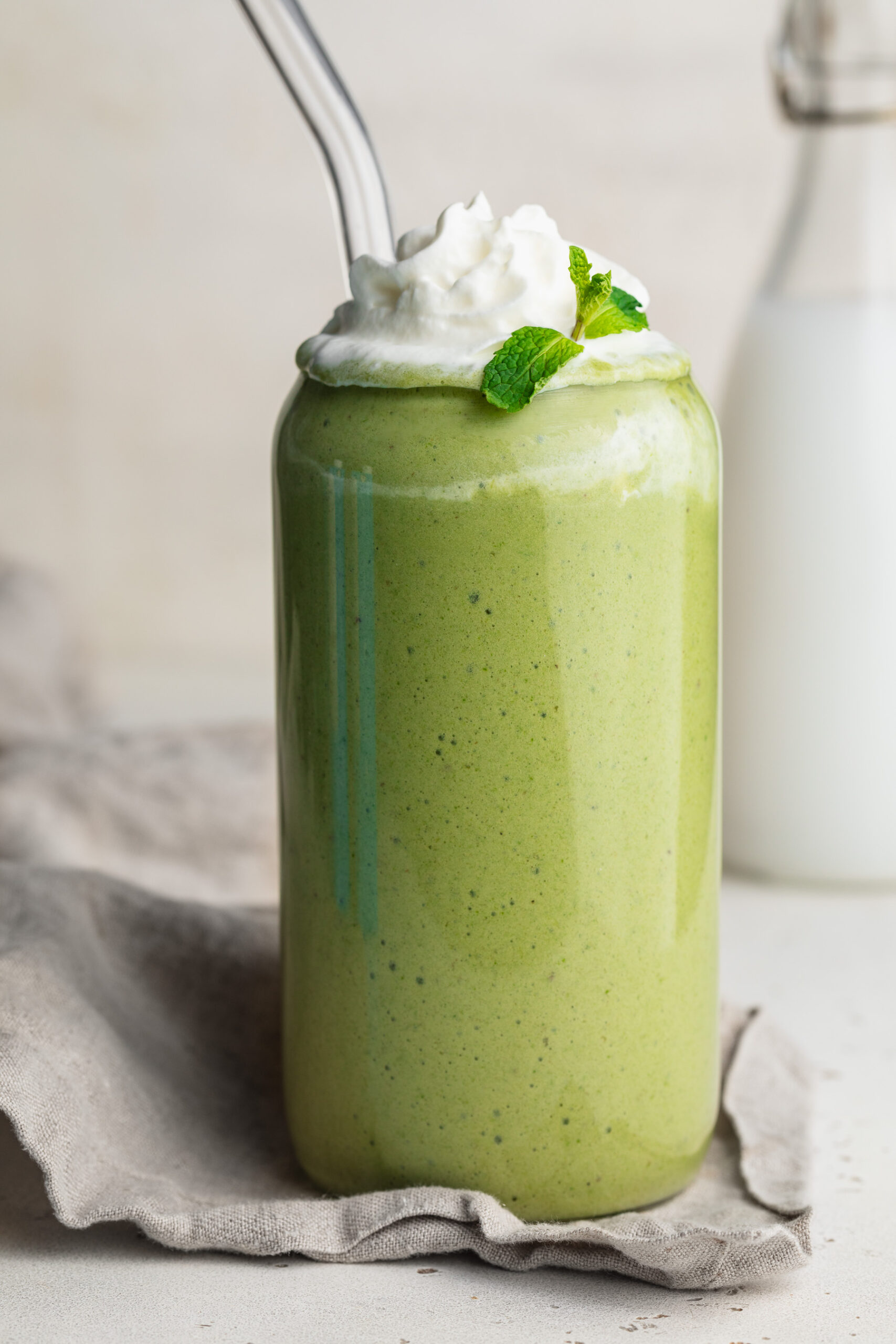 healthy shamrock shake in a glass with whipped cream and fresh mint on top.