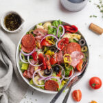 antipasto salad in a bowl with red wine on the side