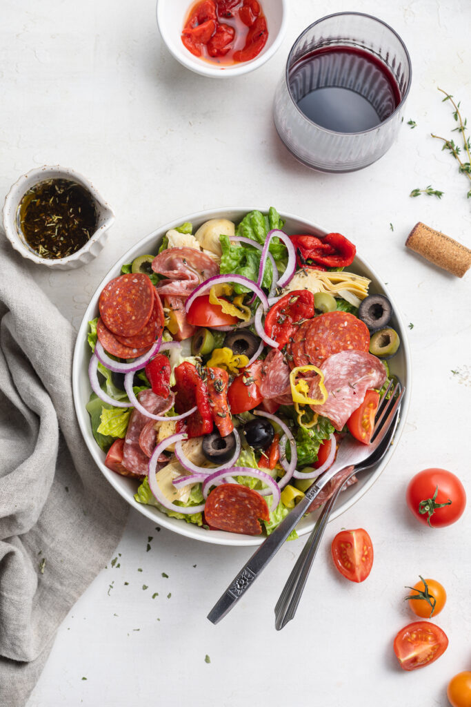 antipasto salad in a bowl with red wine on the side