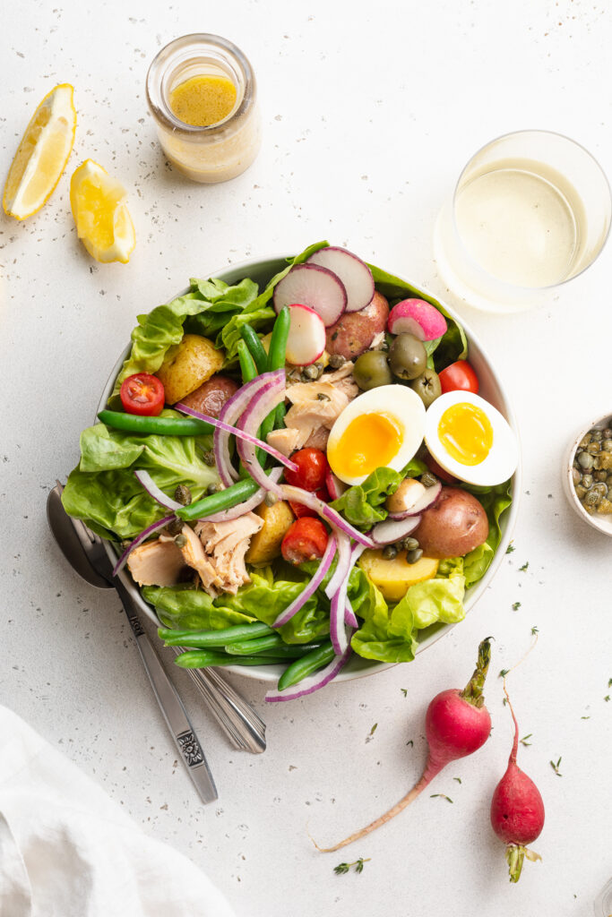 overhead image of nicoise salad in a bowl with dressing on the side.