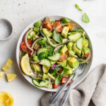 overhead image of avocado salad in a bowl with lemon on the side