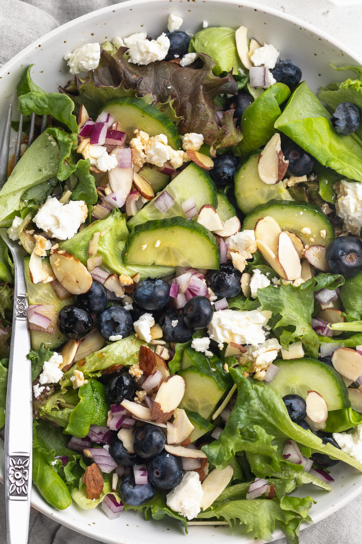 Spring Mix Salad with Blueberries, Almonds, Feta, and Honey Vinaigrette Close-up overhead image of spring mix salad in a bowl.