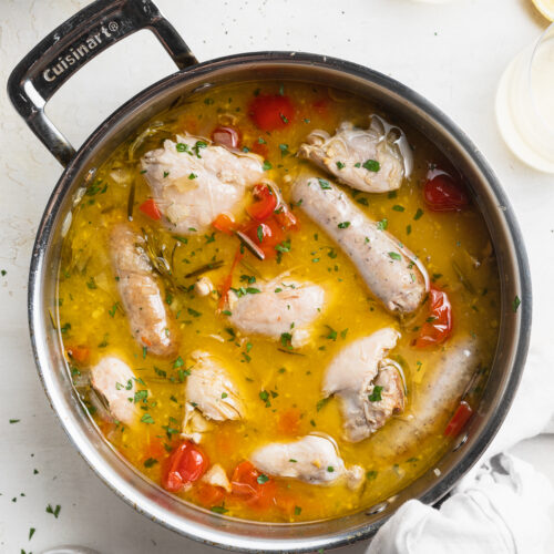 overhead image of chicken scarpariello in a skillet with crispy potatoes on the side.