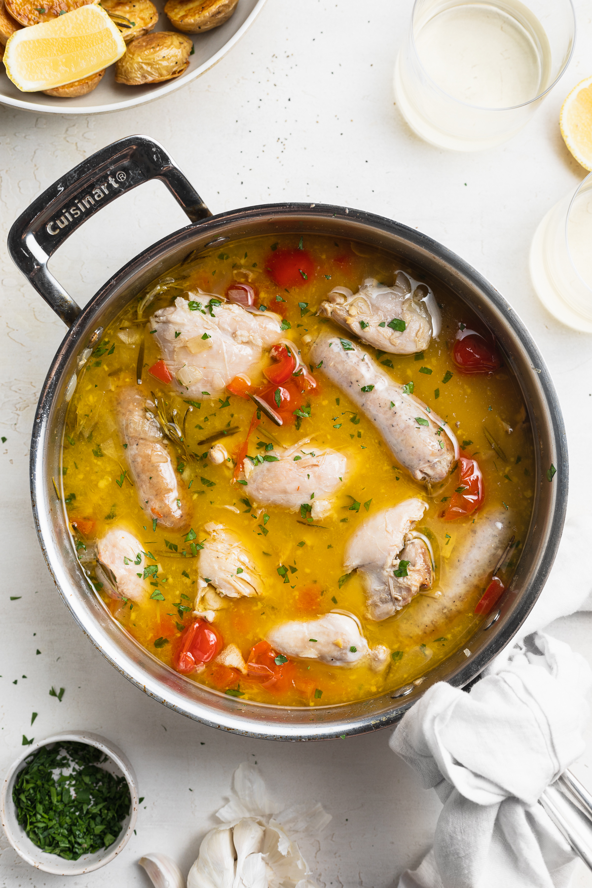 overhead image of chicken scarpariello in a skillet with crispy potatoes on the side.