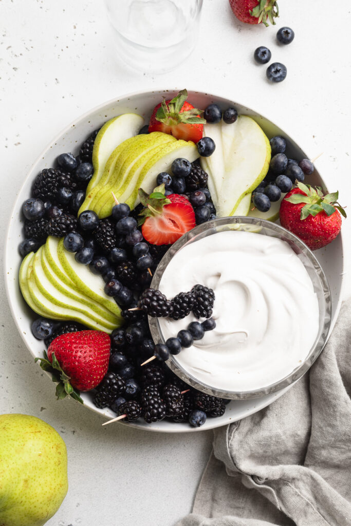 overhead image of marshmallow fruit dip in a bowl with berries and sliced pears.