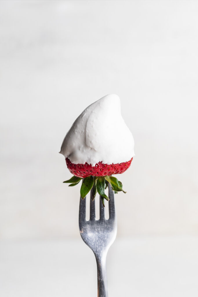 marshmallow fruit dip on a fresh strawberry, on a fork.