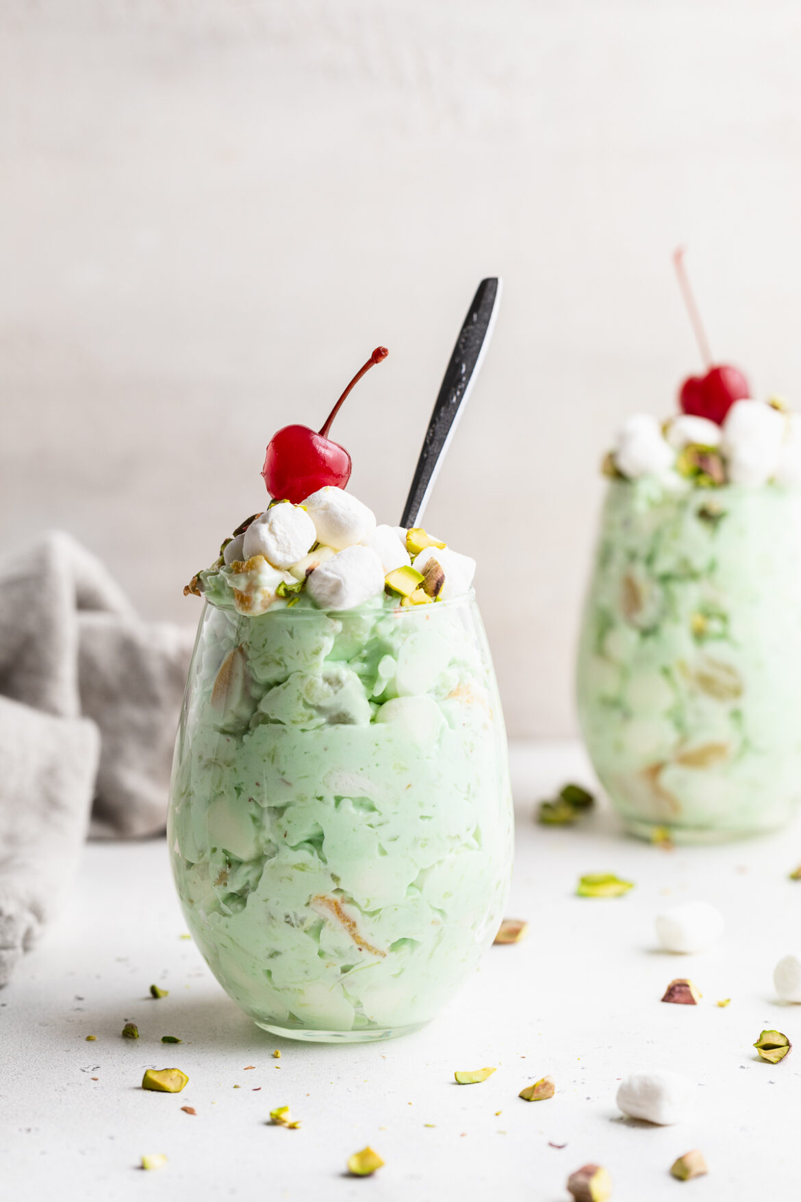 Mom’s BEST Watergate Salad two glasses of watergate salad with cherries on top