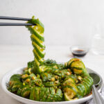 spiralized cucumber being lifted off a plate of asian cucumber salad