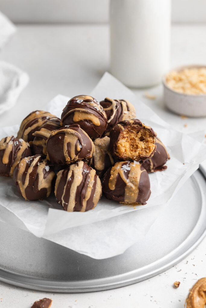 crunchy peanut butter balls stacked on parchment paper with milk on the side.