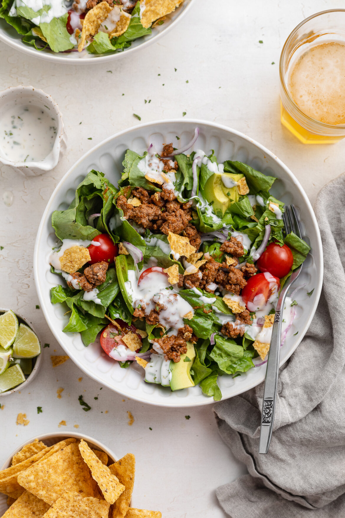 Easy Healthy Taco Salad with Creamy Cilantro-Lime Dressing overhead image of a taco salad with chips and beer on the side.