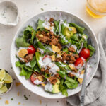 overhead image of a taco salad with chips and beer on the side.