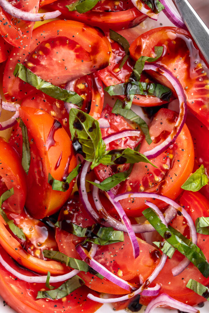 super close-up image of tomato salad with fresh basil on top.