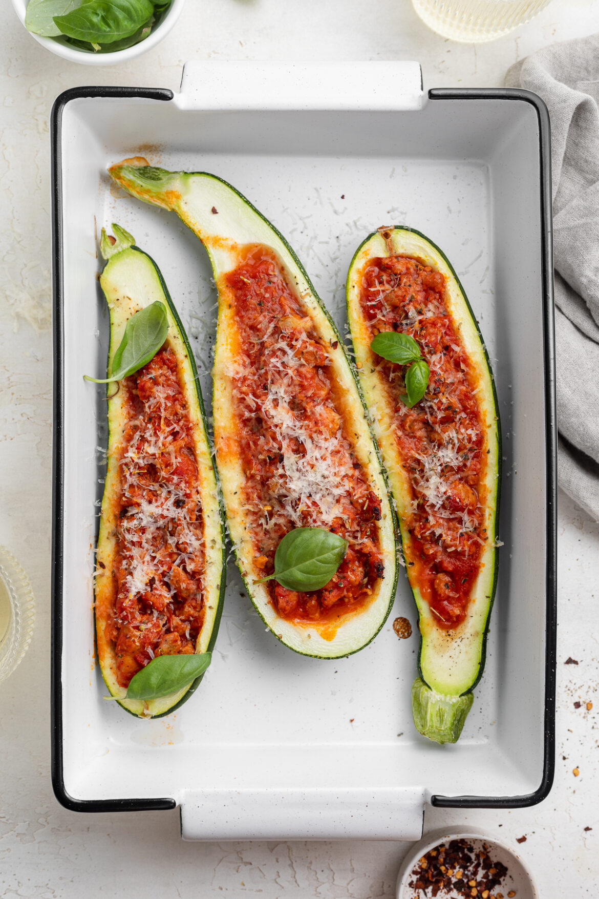 Italian Stuffed Zucchini Boats close up image of stuffed zucchini boats in a baking dish with fresh basil on top.