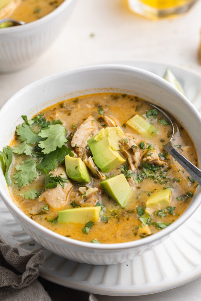 close-up image of Instant Pot white chicken chili in a bowl with avocado and cilantro on top.
